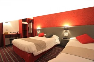 Habitación de hotel con dos camas, un escritorio y una silla.