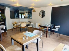 Un comedor con varias mesas y sillas, un gran reloj de pared y una ventana con vistas al exterior.