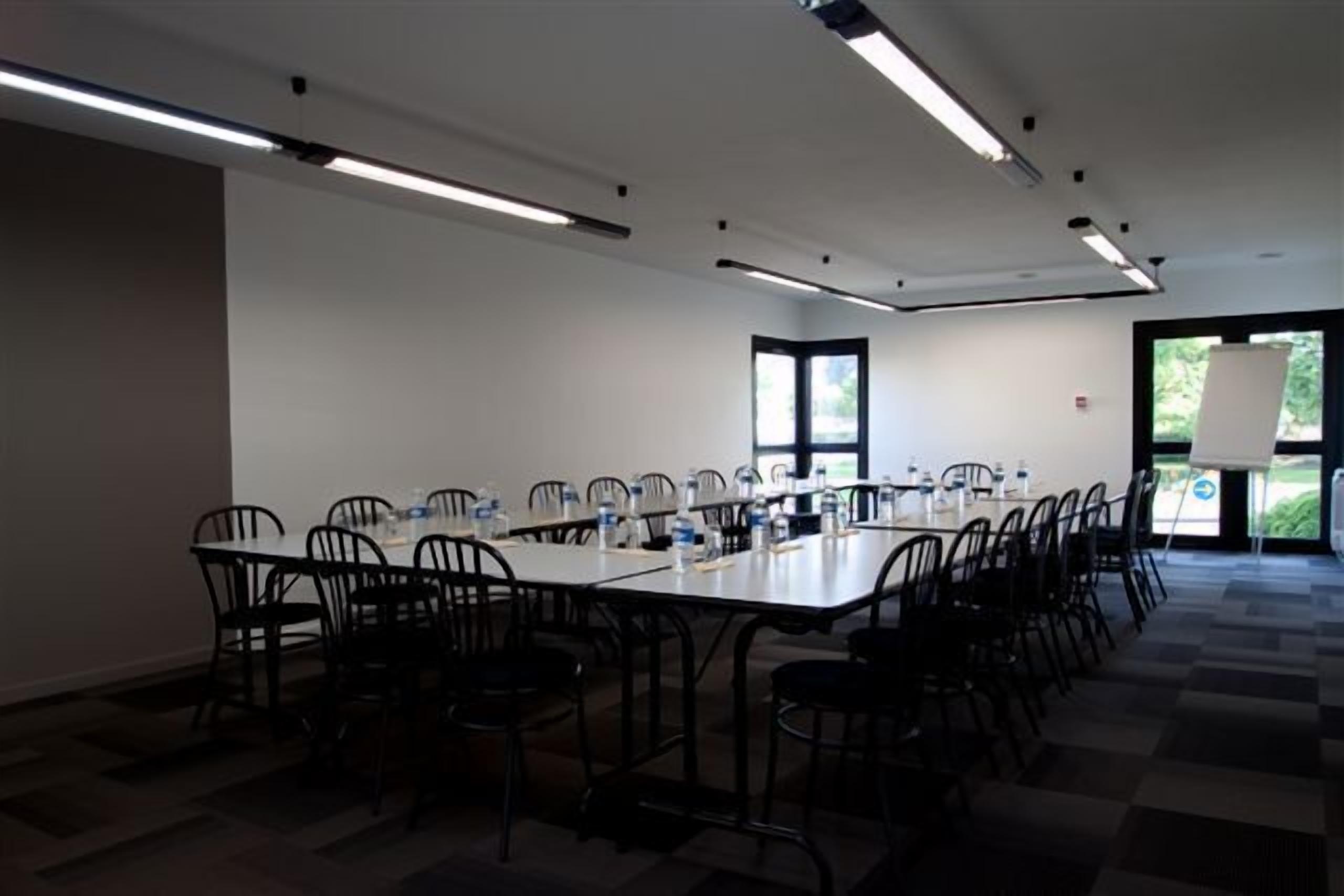 A conference room with a long table, chairs, and a projector screen.