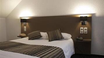 A hotel room with a large bed, two bedside lamps, a nightstand, and a wall-mounted phone.