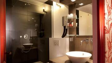 A modern bathroom with a glass-enclosed shower, a white sink, and a mirror above the sink.