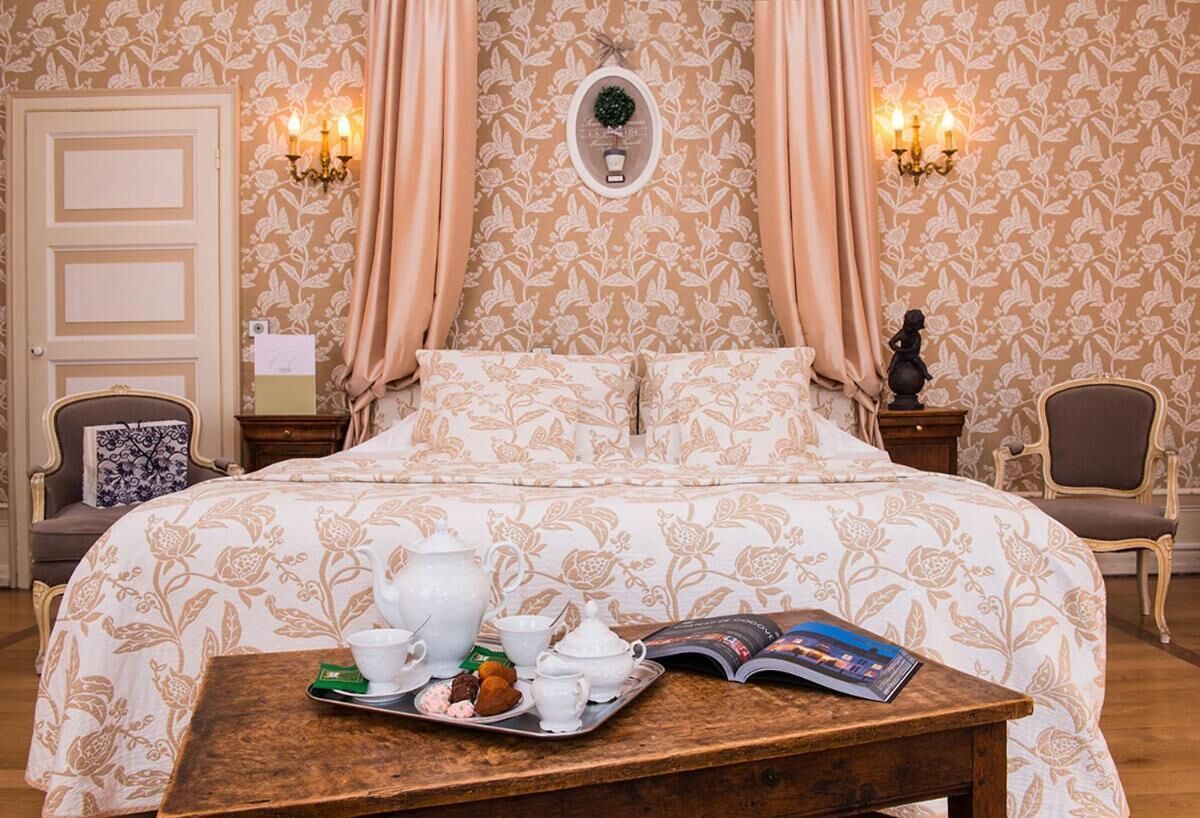 Une chambre à coucher avec un lit, une table de chevet sur laquelle se trouve un plateau avec du thé et des accessoires, et un livre.