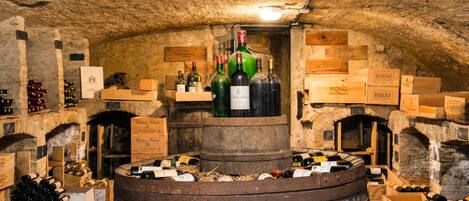 Un sótano con cajas de madera y barriles que contienen botellas de vino.