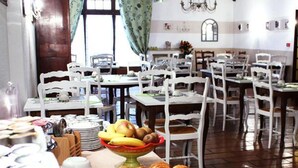 Un comedor con varias mesas y sillas, una variedad de alimentos a la vista, y una araña en el techo.