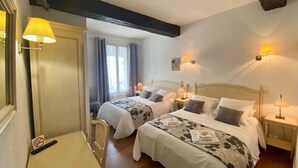 Habitación de hotel con dos camas, un escritorio y una silla. Hay dos mesitas de noche con lámparas.