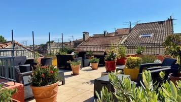 A rooftop terrace with outdoor seating and potted plants.