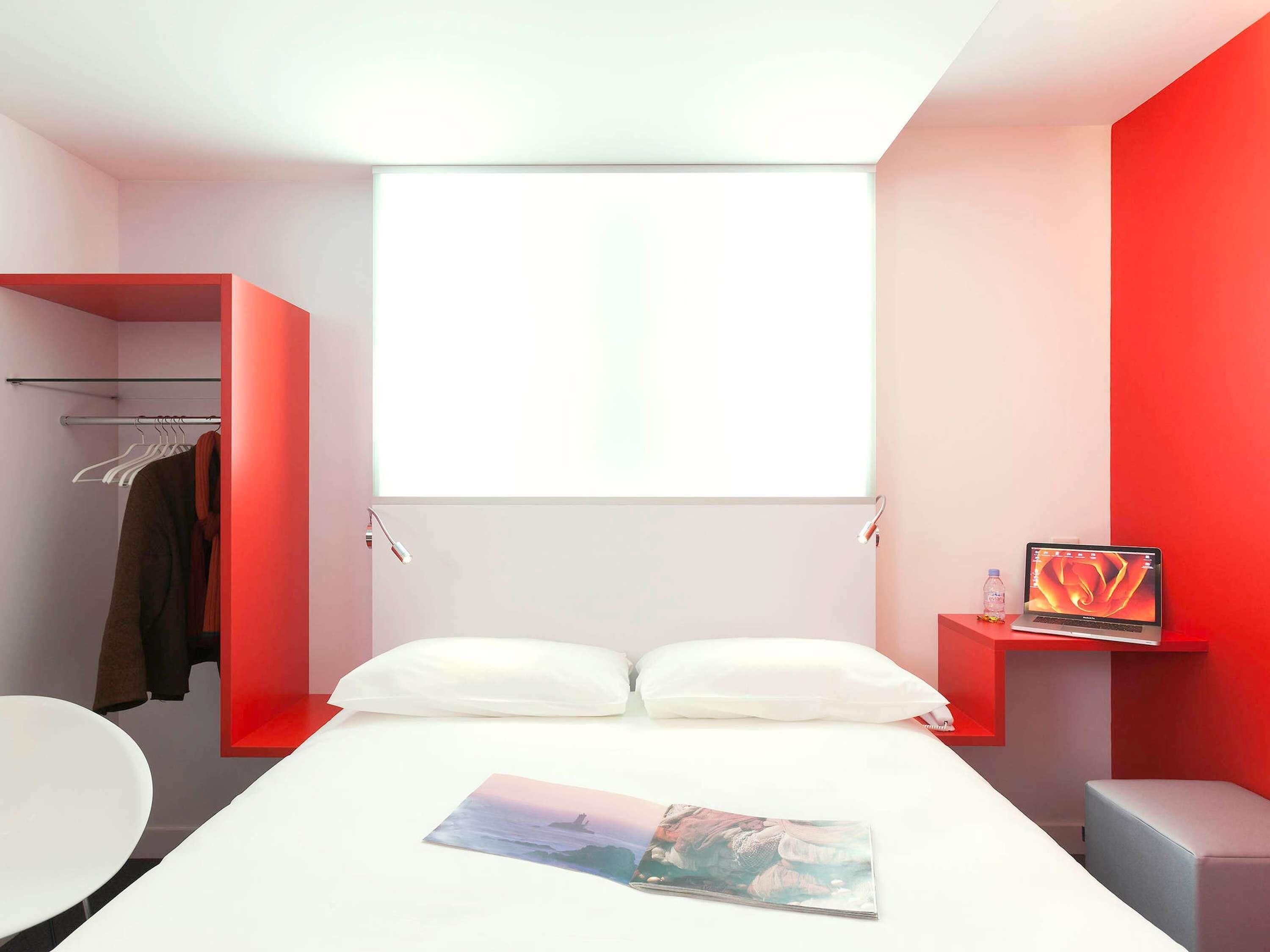 Ein modernes Hotelzimmer mit einem Bett, einem Schreibtisch, einem Stuhl, einem Kleiderschrank und einem Fenster.