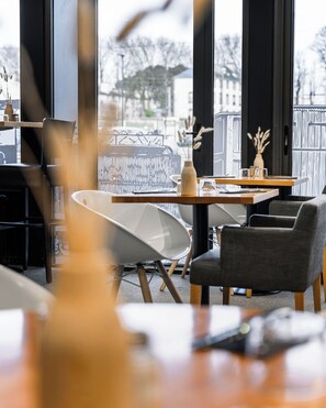 Un interior moderno con una zona de comedor que presenta una mesa de madera, una silla blanca y un sillón oscuro.