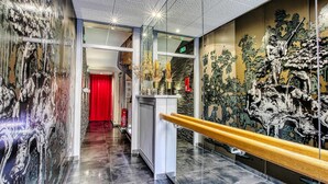 Ein moderner Hotelgang mit Glastrennwand, rotem Vorhang und Wanddekoration.