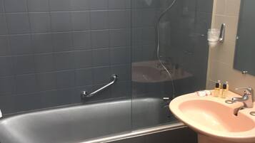 Un baño con bañera, lavabo y espejo.