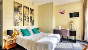 Een hotelkamer met een bed, een bureau, een stoel, een televisie en kunstwerken aan de muren.