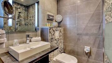 A modern bathroom with a large sink, a toilet, and a shower area.