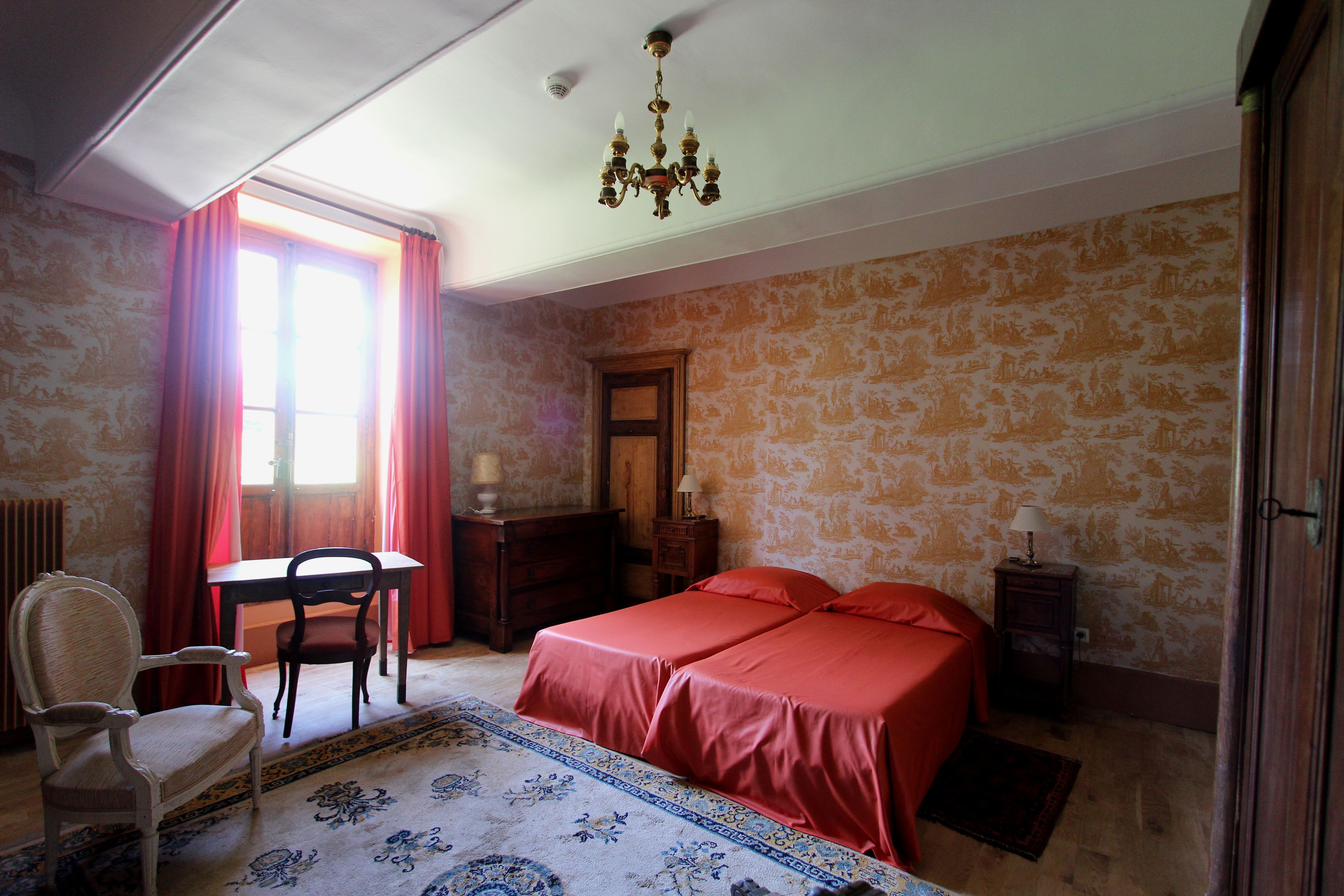 Un dormitorio con una cama, una silla, una mesa y un aparador.