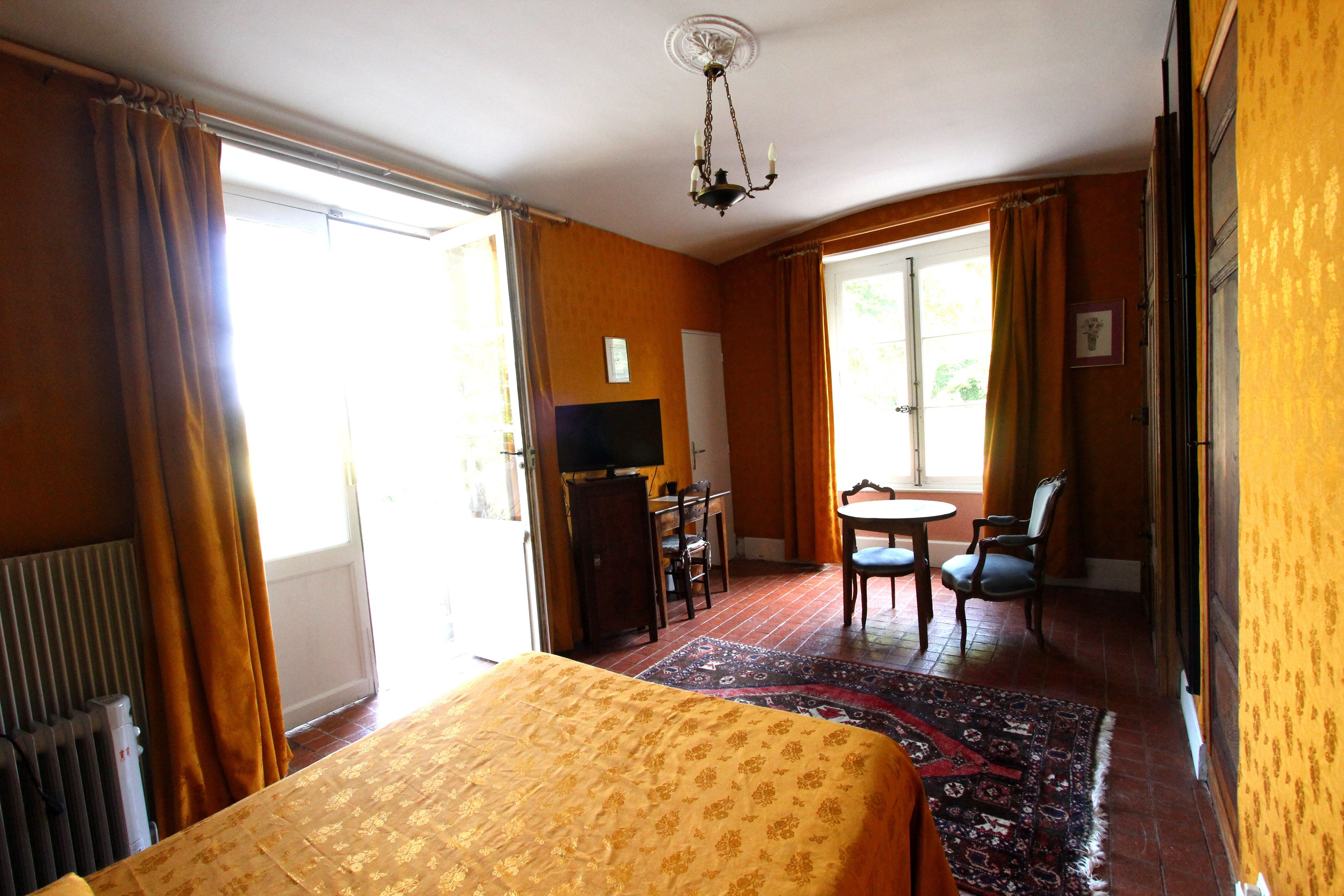 Een hotelkamer met een bed, een bureau, een stoel, een televisietoestel en uitzicht op de omgeving.