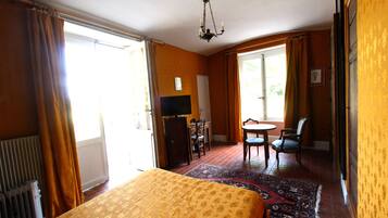 Een hotelkamer met een bed, een bureau, een stoel, een televisietoestel en uitzicht op de omgeving.