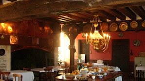 A restaurant with wooden beams, a chandelier, and a variety of dishes on the tables. - Château d'Island Avallon Vézelay (Island)