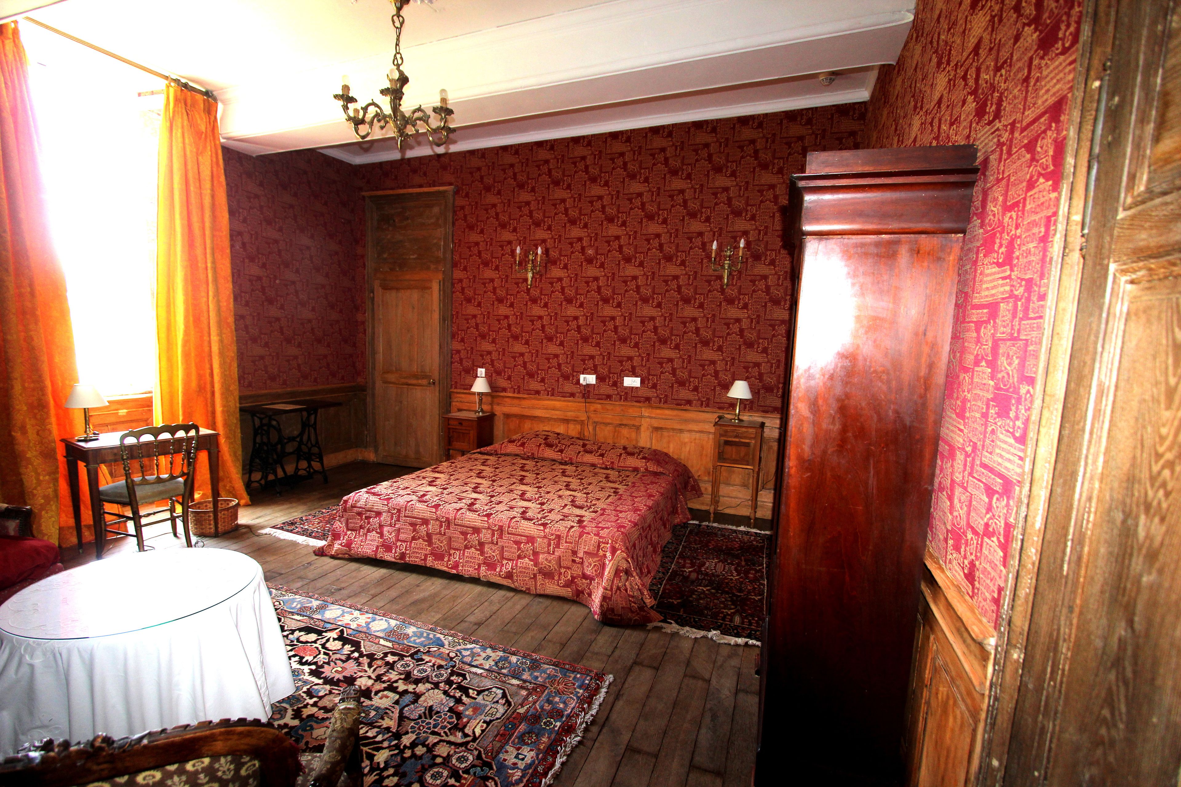 Una habitación tradicional con una cama de madera, una mesa redonda y una alfombra estampada.