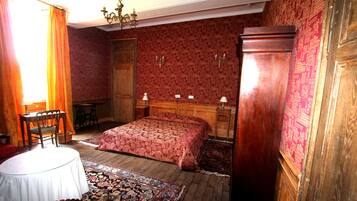 Una habitación tradicional con una cama de madera, una mesa redonda y una alfombra estampada.