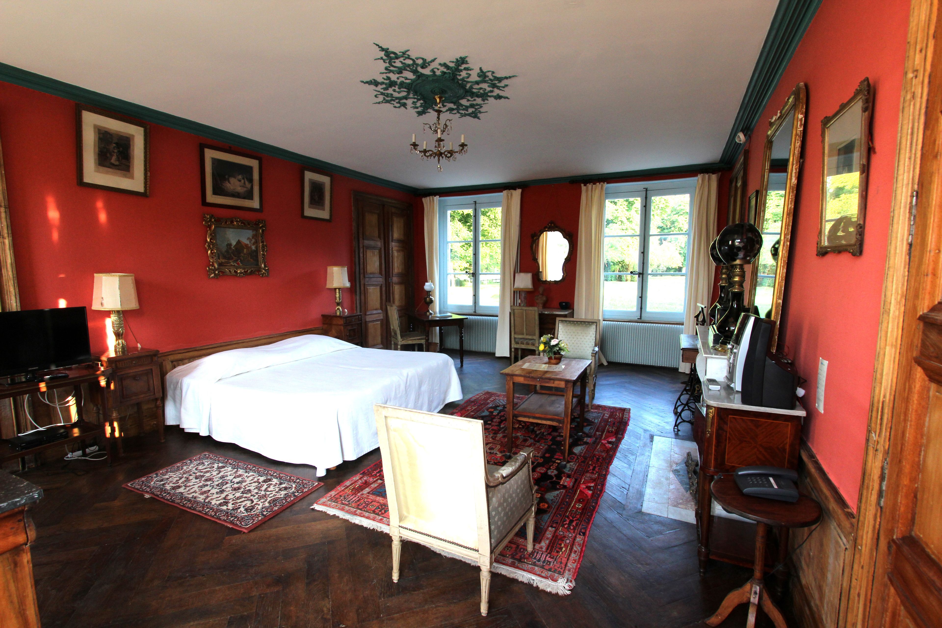 Une pièce comprenant un lit, un bureau, une chaise, une lampe et un miroir.