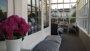 A sunlit room with large windows, a white potted plant, a bench, and wicker chairs. - Marlborough Hotel (Shanklin)