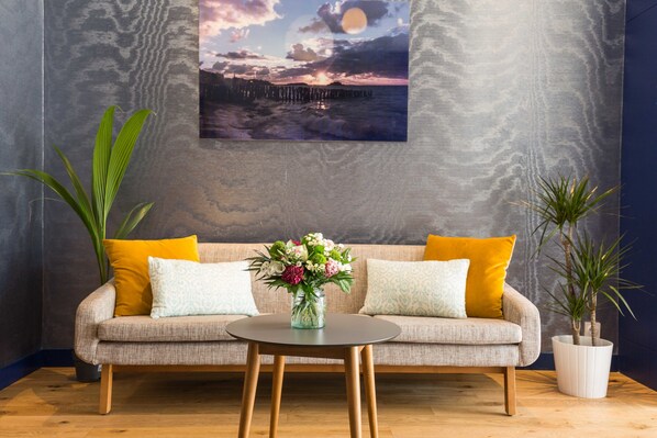 Una sala de estar moderna con un sofá, una mesa redonda y un jarrón de flores.