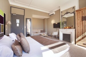 Een hotelkamer met een bed, een bank, een open haard, een televisie en een spiegel.