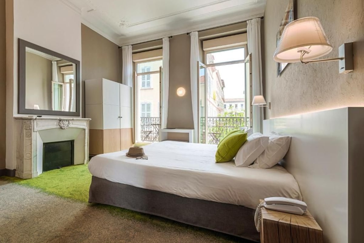 A hotel room with a large bed, a fireplace, a mirror, and a balcony view.