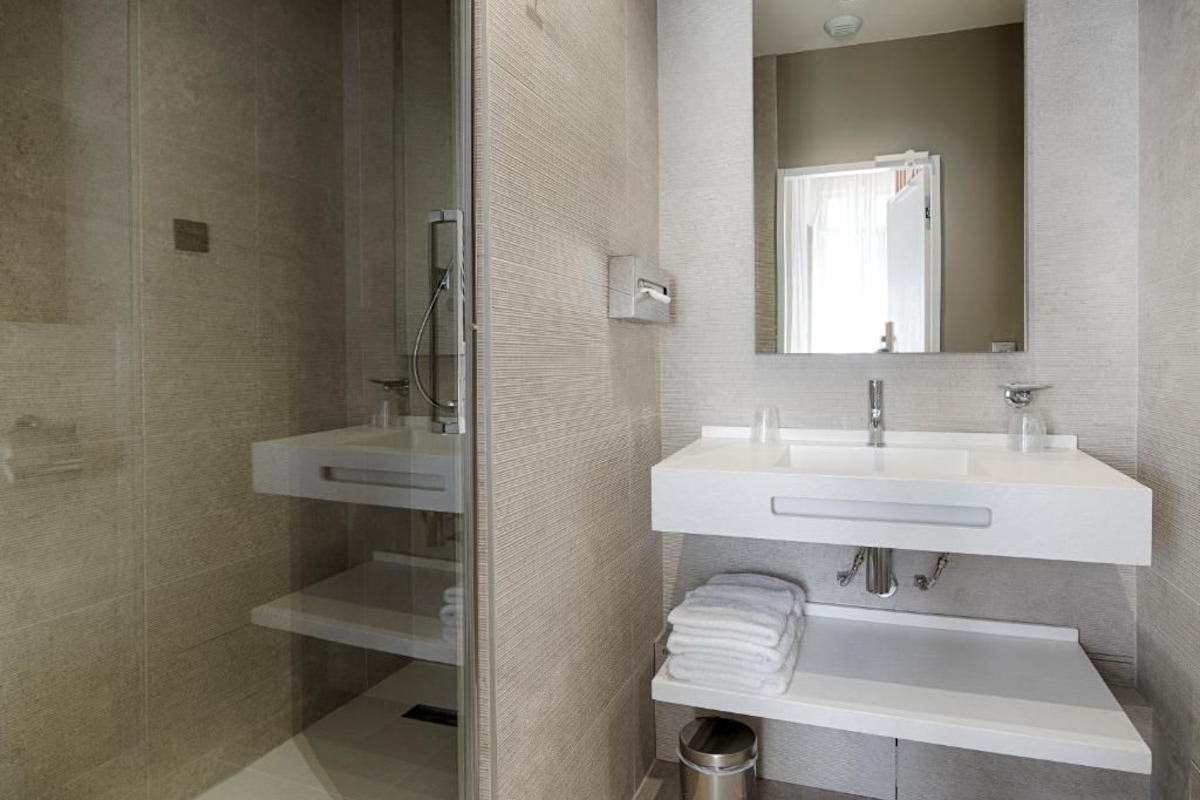 Un baño moderno con cabina de ducha de vidrio, tocador doble y espejo sobre el lavabo.