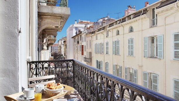A balcony with breakfast items, a wicker basket, and a newspaper. - La Villa Tosca (Cannes)