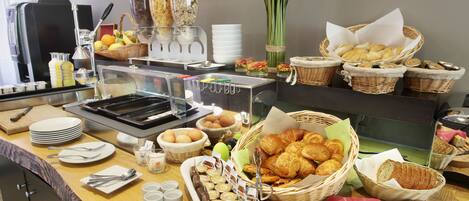 Un buffet proposant une variété de plats, notamment des fruits, des pâtisseries et des condiments.