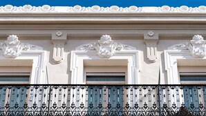 A building facade with ornate white architectural details, including decorative moldings and a wrought iron balcony railing. - La Villa Tosca (Cannes)