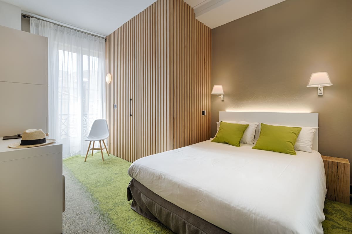 A modern hotel room with a large bed, a desk, and a chair.