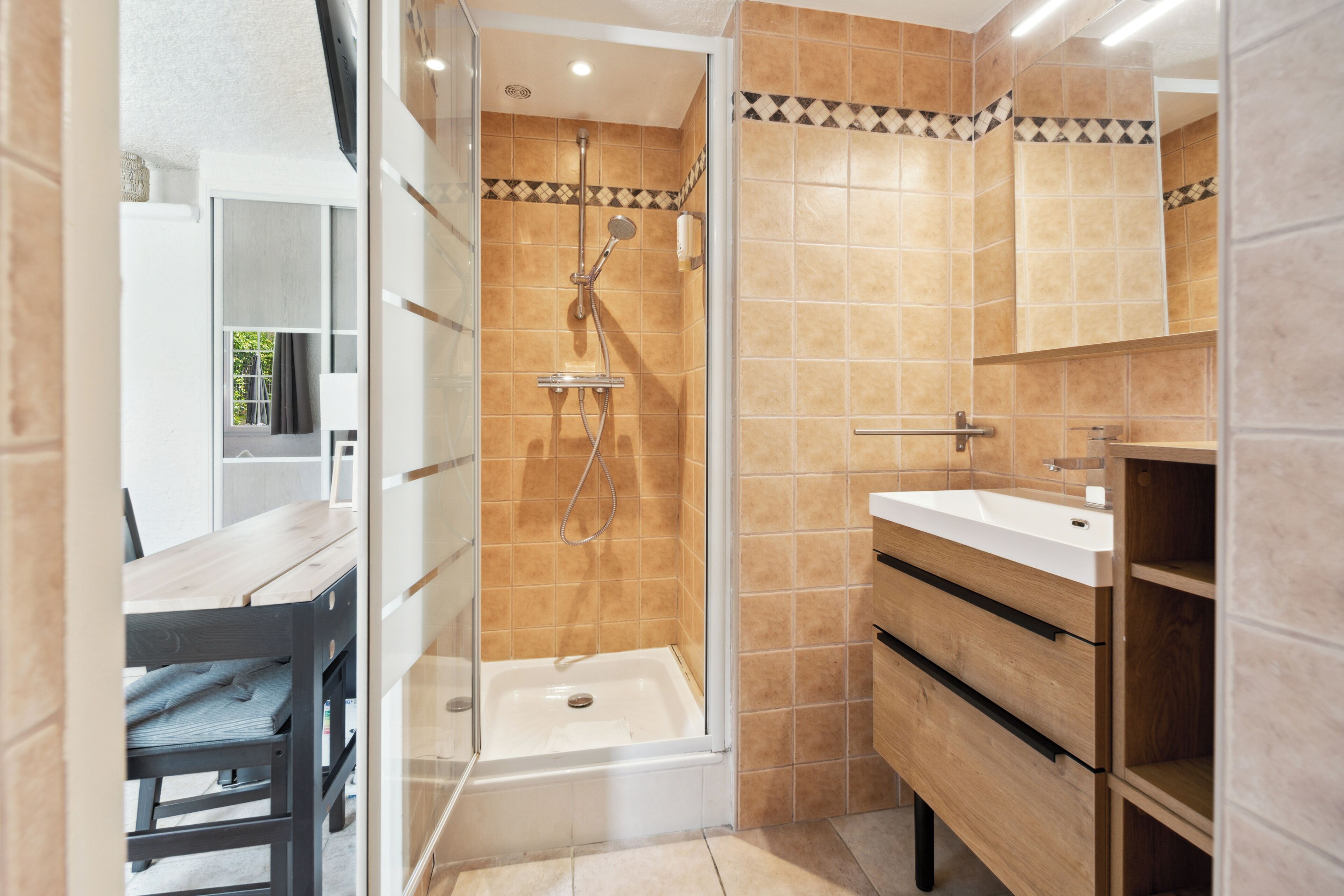 Un baño moderno con ducha acristalada, tocador de madera e lavabo.