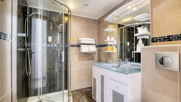 A modern bathroom with a glass-enclosed shower, a glass sink, and a large mirror.