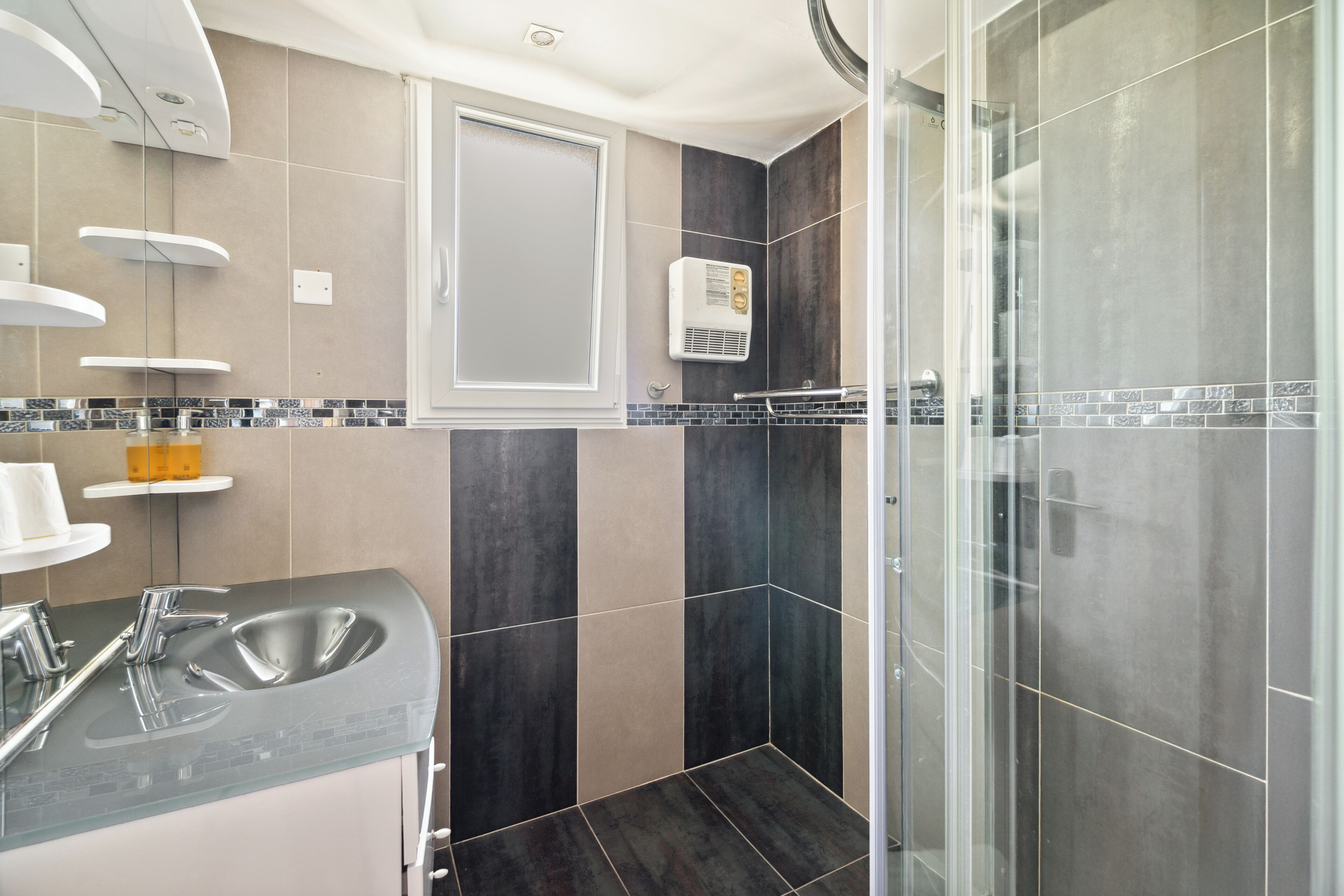 Un baño moderno con cabina de ducha de vidrio, lavamanos empotrado y toallero.
