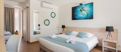 A hotel room with a large bed, a desk, a chair, a mirror, and a painting on the wall.
