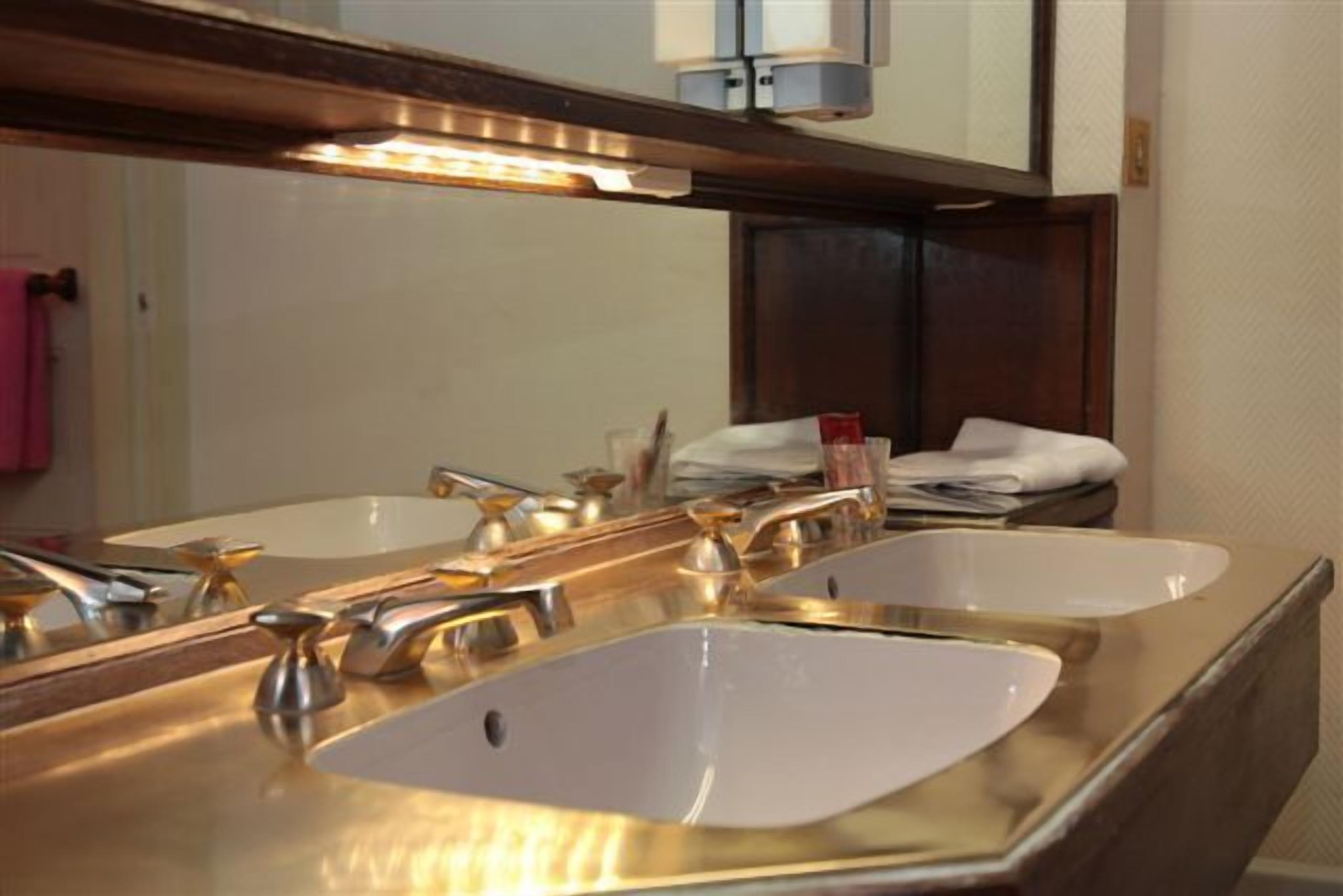 Un baño con dos lavamanos, un espejo y un perchero para toallas.