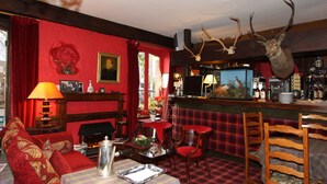 Ein gemütlicher Raum mit roter Wand, Kamin, Barbereich und einem aufgehängten Hirschkopf.