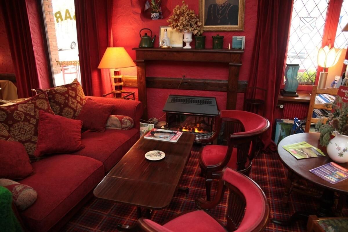 A cozy living room with a red sofa, a wooden coffee table, and a fireplace.