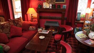 A cozy living room with a red sofa, a wooden coffee table, and a fireplace.
