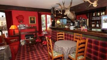 A bar area with a mounted deer head, plaid carpet, wooden chairs, and a red wall.