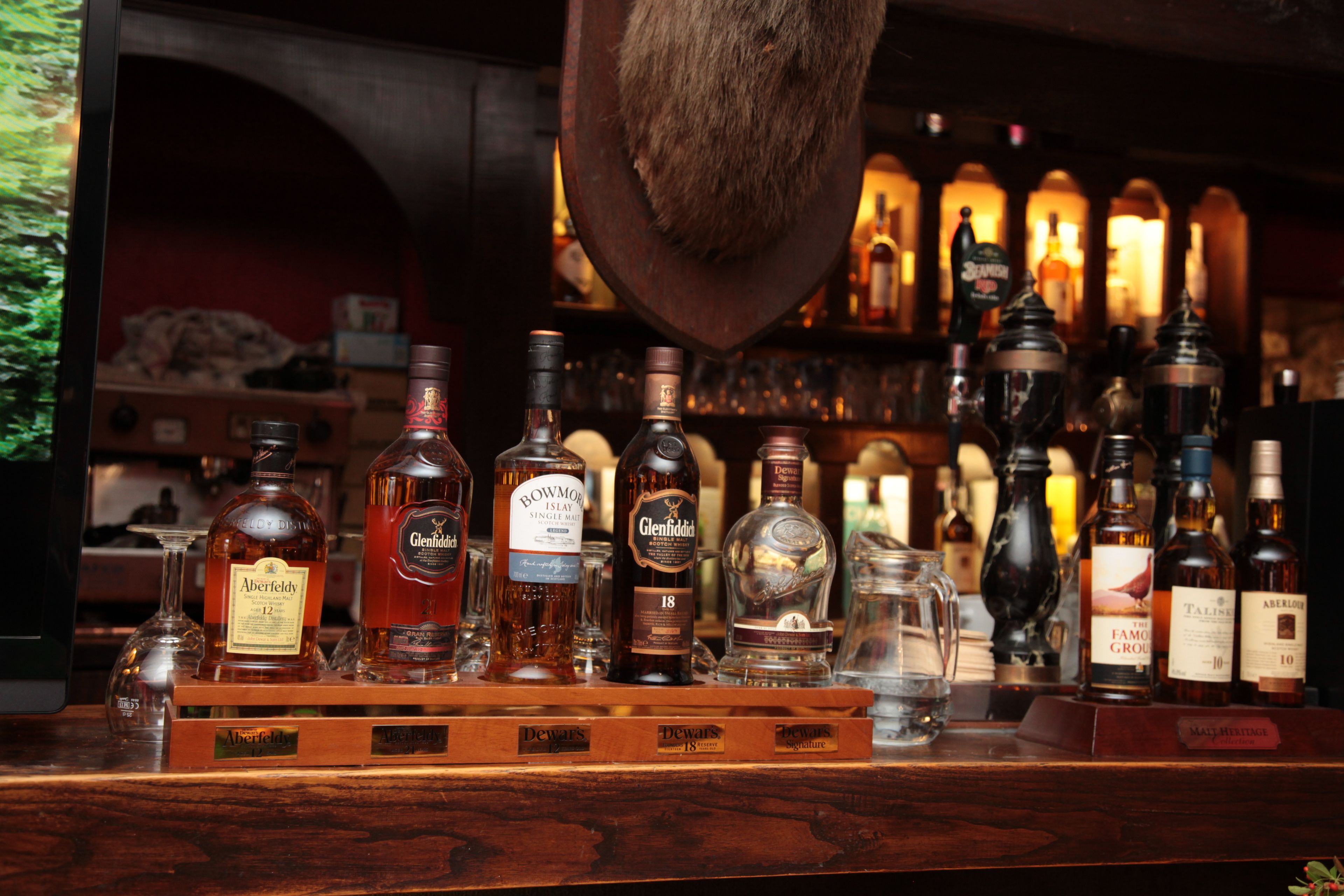 A bar with various bottles of alcohol and a wooden counter.