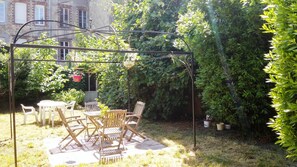 A garden with a pergola, wooden chairs, and a table.