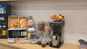 Una cocina equipada con refrigerador, microondas, cafetera y varios alimentos.