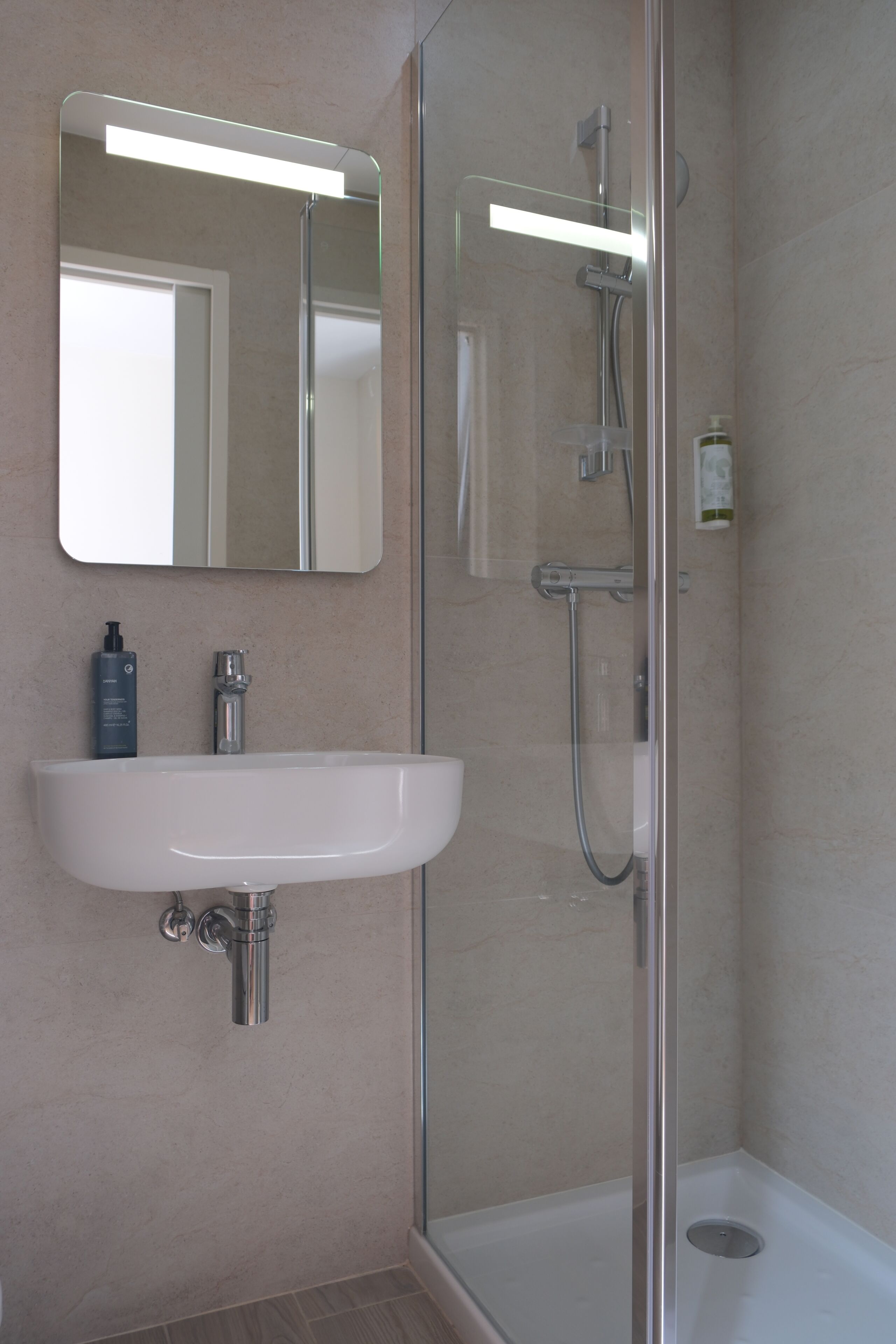 A bathroom with a white sink, a mirror, a shower, and a toilet.