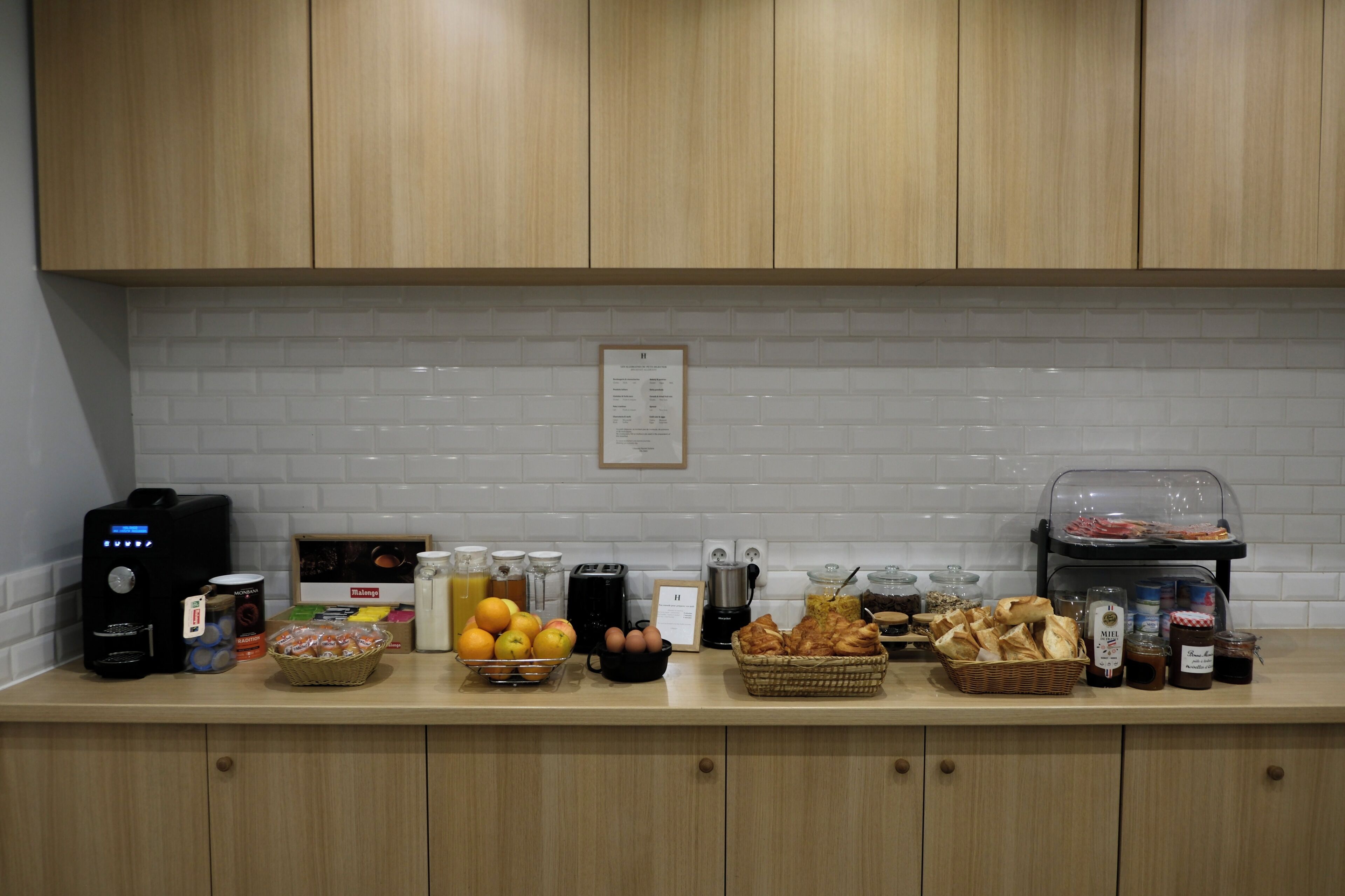 A kitchen counter with various breakfast items, including fruits, bread, and condiments.