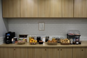 A kitchen counter with various breakfast items, including fruits, bread, and condiments. - Hipotel Paris Voltaire Bastille (Paris)