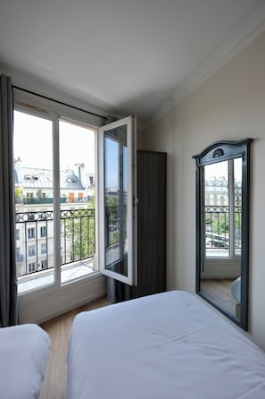 A hotel room with a large window, a bed, a wardrobe, and a mirror. - Hipotel Paris Voltaire Bastille (Paris)