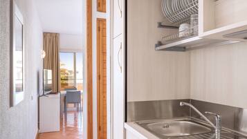 Una cocina moderna con un lavamanos de acero inoxidable, armarios de madera y un escurreplatos.