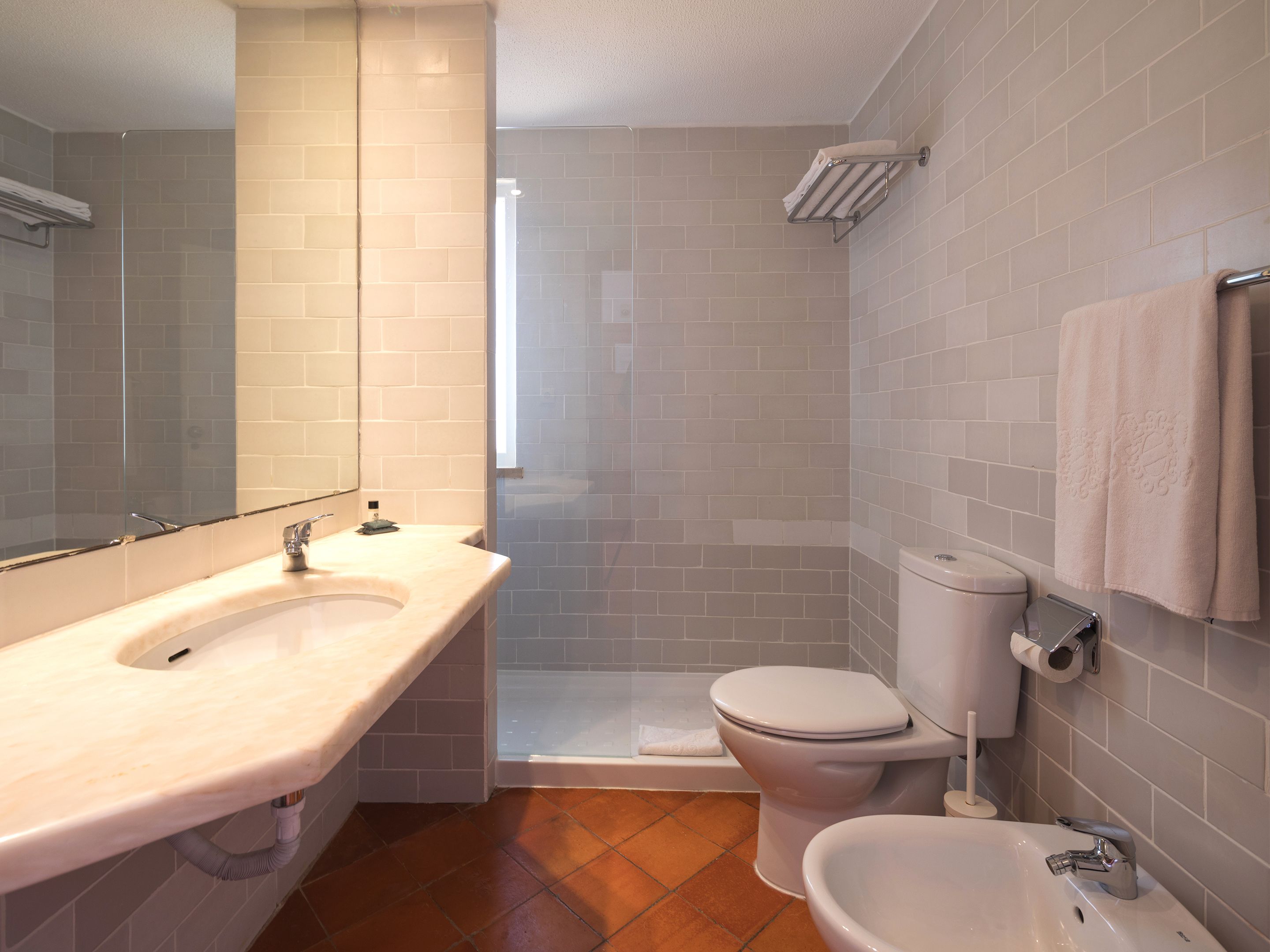 Une salle de bain équipée d’un lavabo, de toilettes, d’un bidet et d’un espace douche.